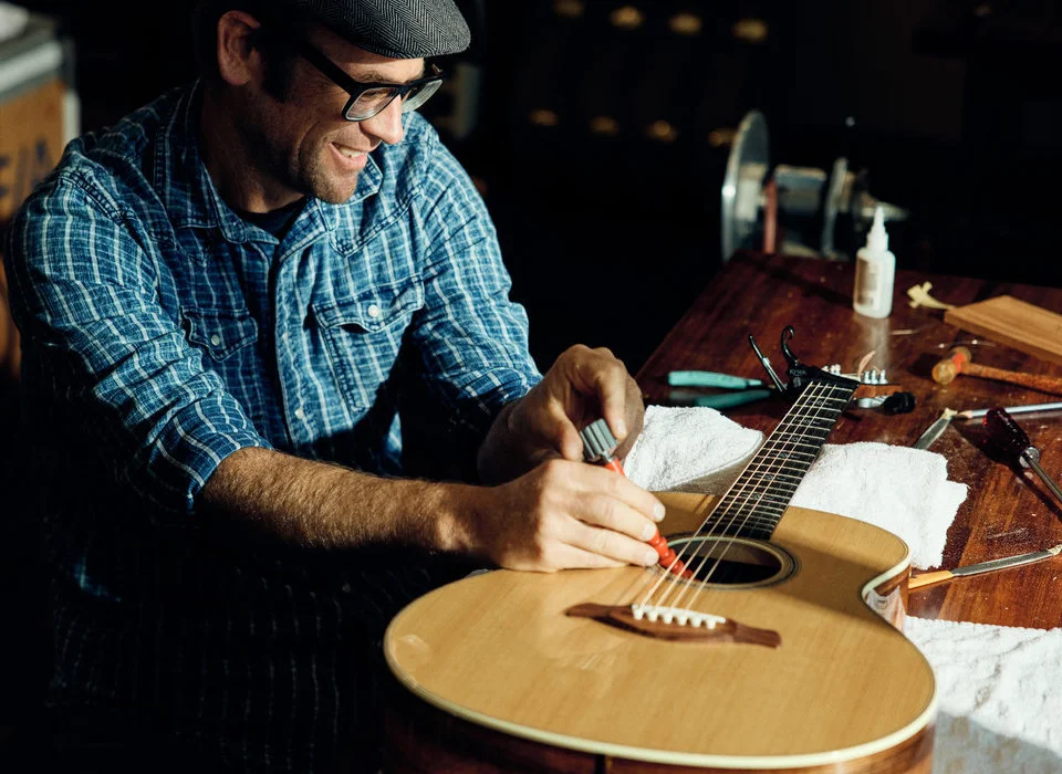 Image of Andy Powers adjusting a Taylor acoustic guitar with an Action Control Neck